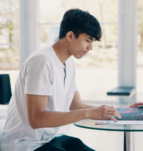 Student reading a booklet at a table